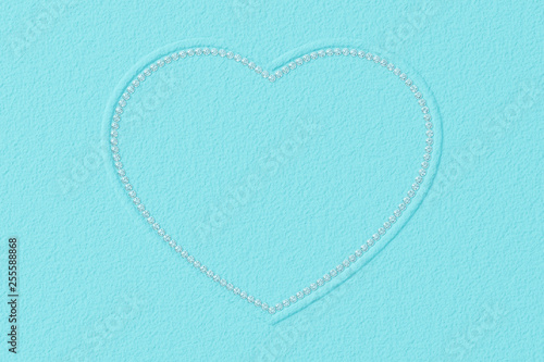 Heart-shaped frame made of small diamonds on turquoise textured background photo