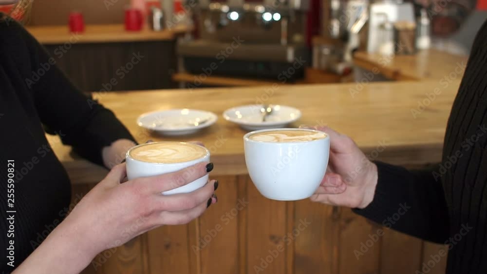 Close-up of a man and a woman holding a Cup of fragrant cappuccino with drawings on the foam, they sit at the bar in a coffee shop. Latte art. Slow motion. Close-up of a man and a woman holding a Cup of fragrant cappuccino with drawings on the foam, they sit at the bar in a coffee shop. Latte art. Slow motion.