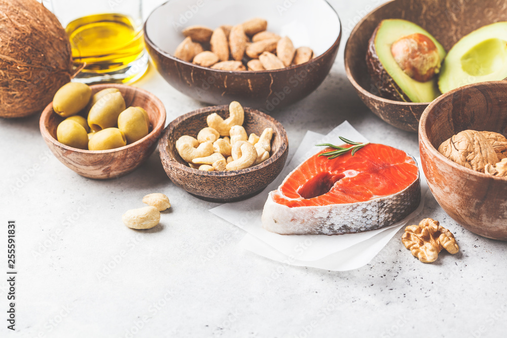 Healthy fat food background. Fish, nuts, oil, olives, avocado on white background.