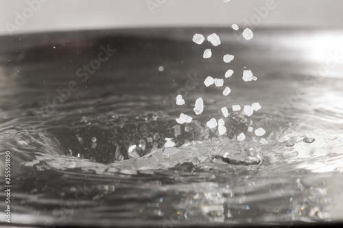 Add salt to boiling water in a metal pan close-up