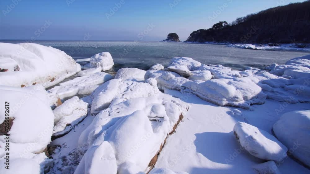Snowy sea shore and cold waves breaking at stones. Marine biospheric reservation at Far East of Russia Snowy sea shore and cold waves breaking at stones. Marine biospheric reservation at Far East of Russia