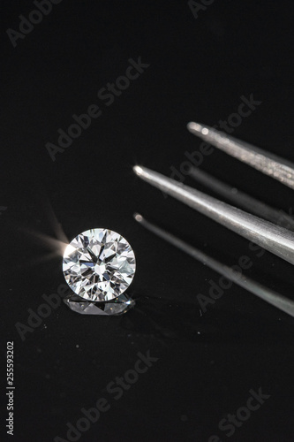 2.50 carat size diamond compared with tweezers on black reflection background