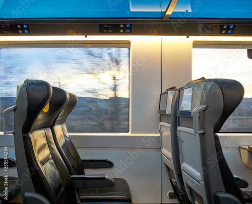View of seats driving train with landscape outside the window. Screens and comfortable travel