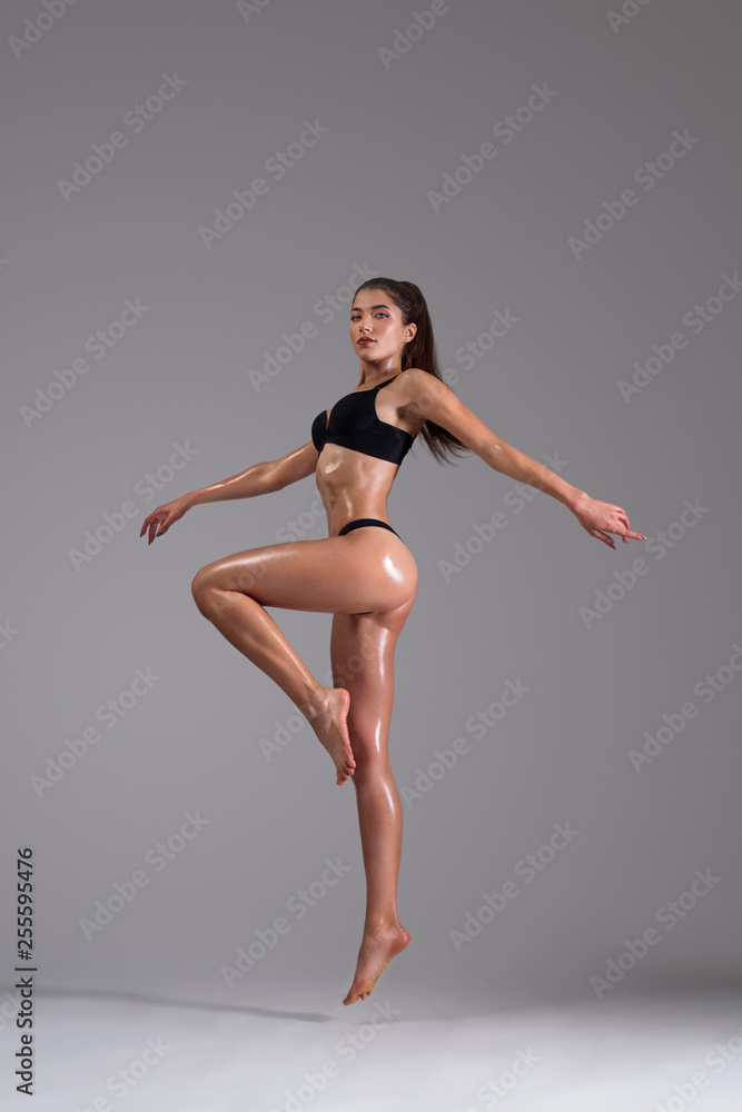 Fitness dancer and fashion model woman in bikini. Female with wet skin in lingerie posing in studio.