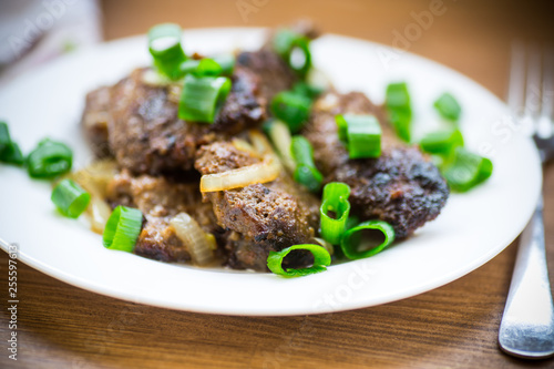 fried liver with onions in a plate on a wooden