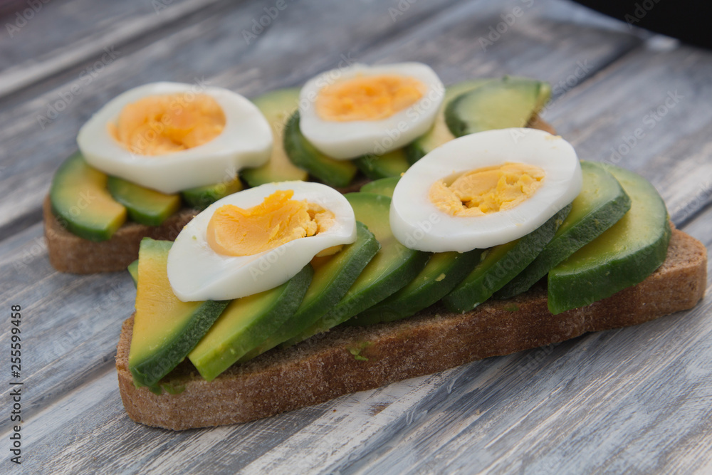 Sandwich with avocado and egg on a wooden background