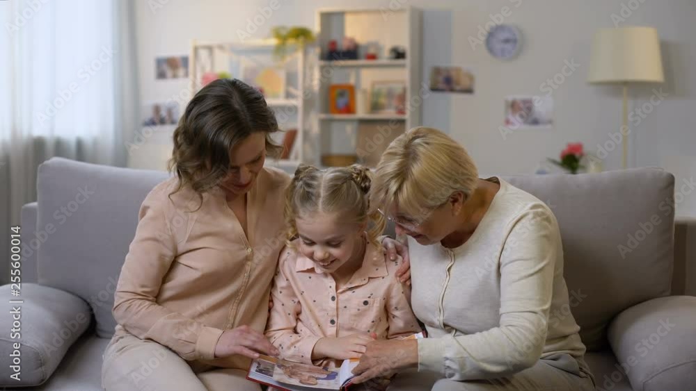 Happy female family members watching photo album pictures, having fun together Happy female family members watching photo album pictures, having fun together