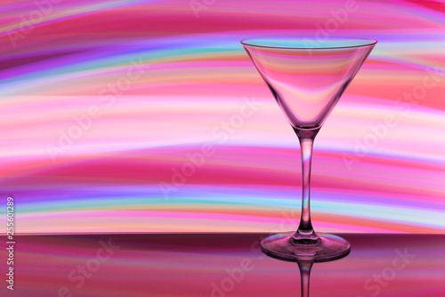 A cocktail / martini glass with colorful streaks of light painting behind