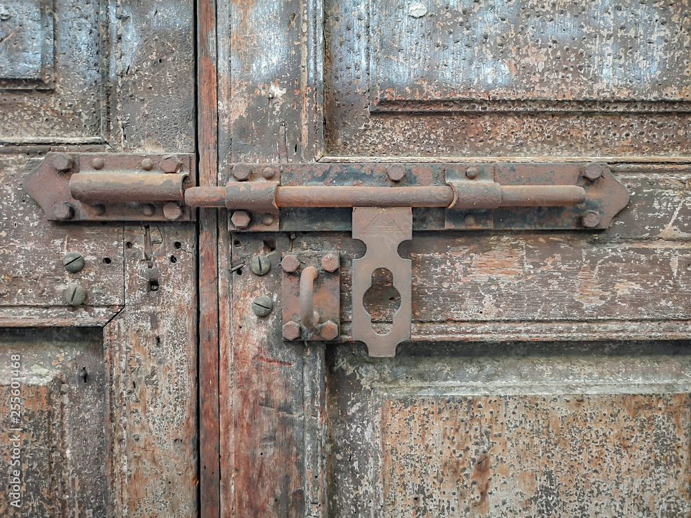 Old metal bolt on the wooden door background.