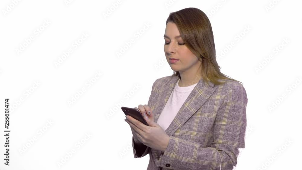 Disappointed sad blonde girl texting on mobile phone while standing isolated over white backgroundchromakey Disappointed sad blonde girl texting on mobile phone while standing isolated over white backgroundchromakey