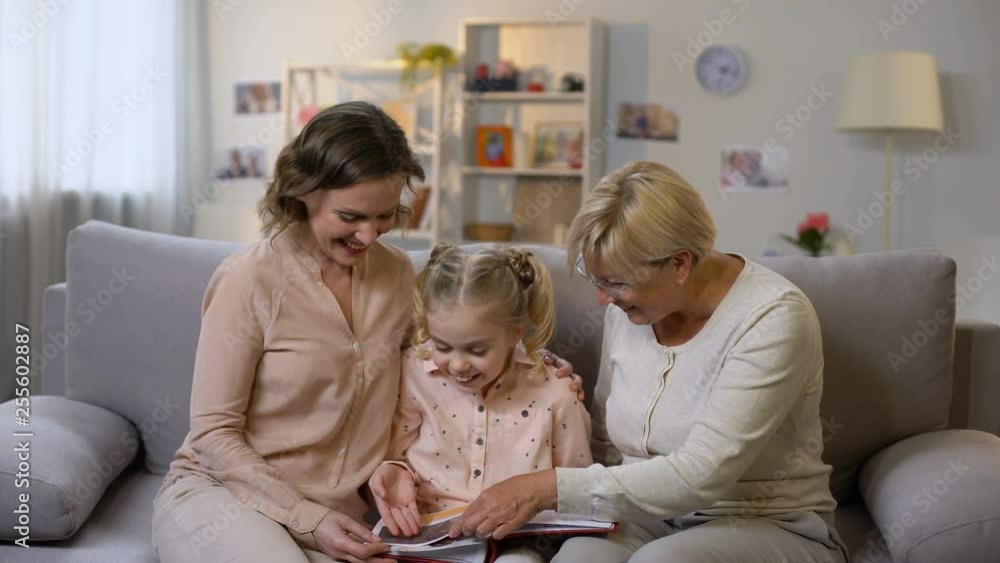 Granny and mother showing photo album pictures to small girl, family history Granny and mother showing photo album pictures to small girl, family history