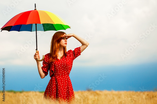Redhead girl with umbrella at field