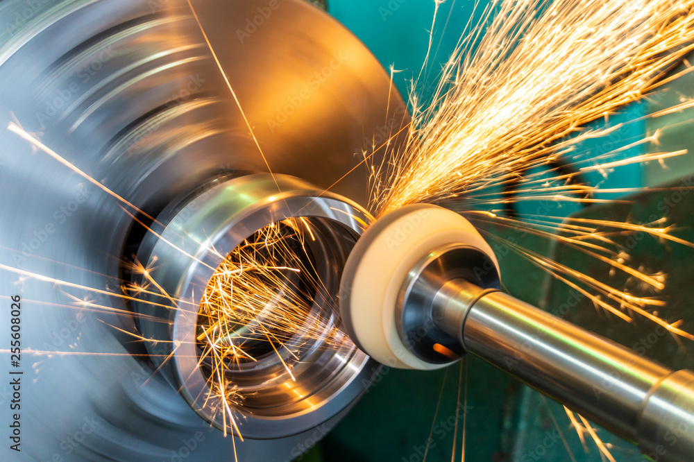 Fototapeta premium End processing of a metal surface with an abrasive stone on a circular grinding machine, sparks fly in different directions.