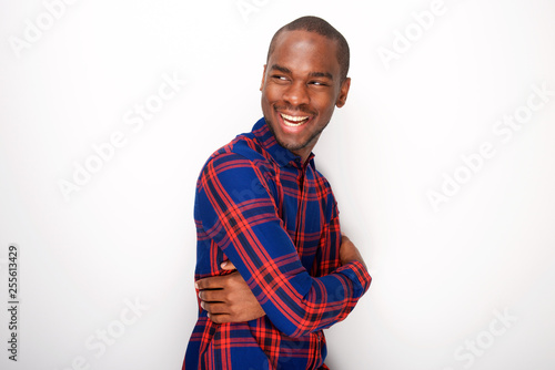 Side of happy young black guy smiling against white wall