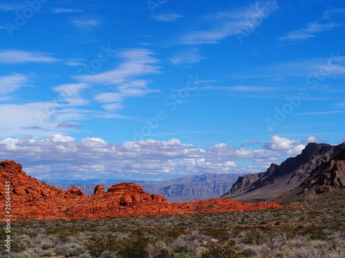 View of red rock and mountains with sky and clouds in valley of fire