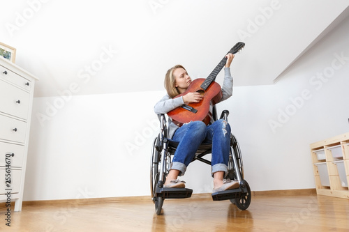 Fotografie, Tablou Disabled young woman in wheelchair playing the guitar.