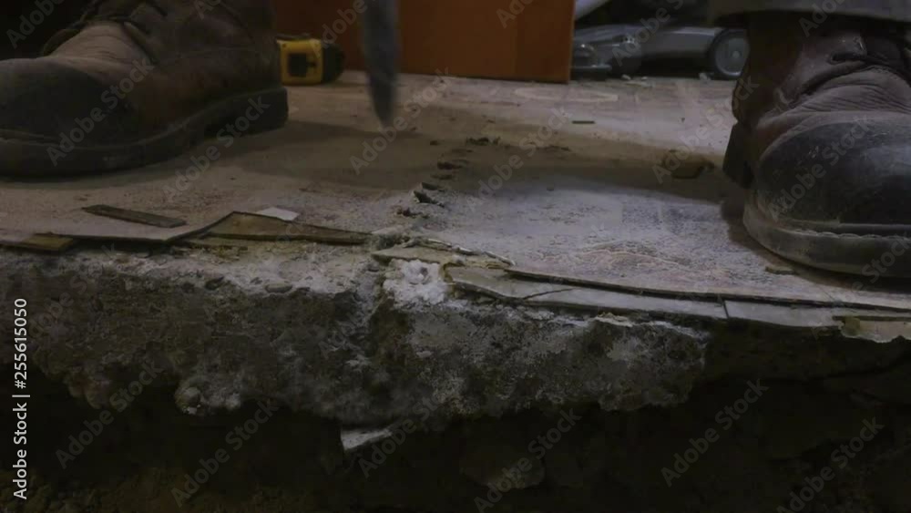 Medium close up on drill bit breaking through basement concrete floor, creating debris Medium close up on drill bit breaking through basement concrete floor, creating debris