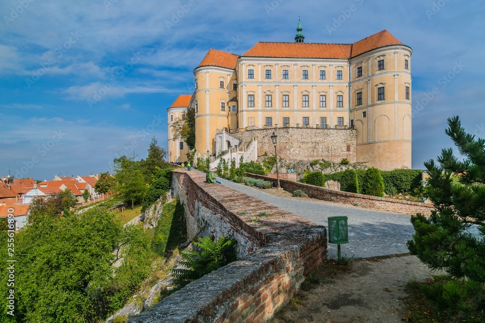 Mikulov, Czech Republic / South Moravia - October 15 2016: Mikulov castle with yellow and white facade and red roof standing on a rock, it is the dominant of the town skyline, brick wall, green bushes