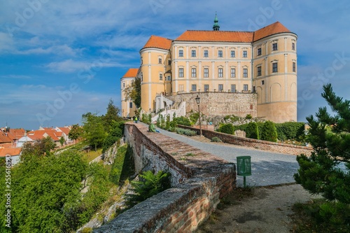 Mikulov, Czech Republic / South Moravia - October 15 2016: Mikulov castle with yellow and white facade and red roof standing on a rock, it is the dominant of the town skyline, brick wall, green bushes