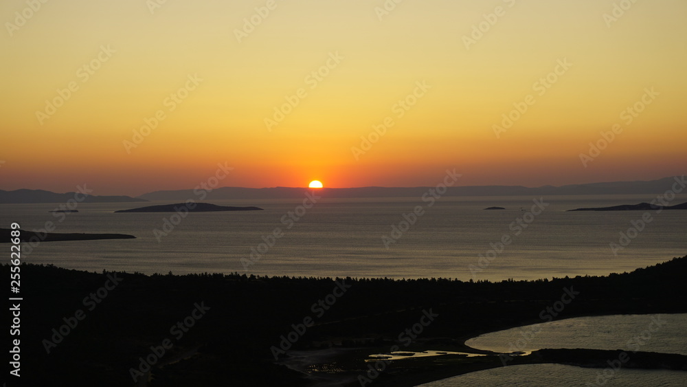 Blazing sunset over Aegean Sea (Ege Denizi) in Seytan Sofrasi (Devil's Table), Ayvalik, Turkey. Bright dramatic sky, dark ground. Scenic colorful sky at sunset landscape. Sun over skyline, horizon.