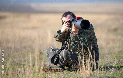 Wildlife, nature man photographer in camouflage outfit shooting, taking pictures