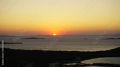 Blazing sunset over Aegean Sea (Ege Denizi) in Seytan Sofrasi (Devil's Table), Ayvalik, Turkey. Bright dramatic sky, dark ground. Scenic colorful sky at sunset landscape. Sun over skyline, horizon. © Akin Ozcan