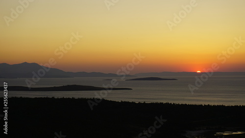 Blazing sunset over Aegean Sea (Ege Denizi) in Seytan Sofrasi (Devil's Table), Ayvalik, Turkey. Bright dramatic sky, dark ground. Scenic colorful sky at sunset landscape. Sun over skyline, horizon.