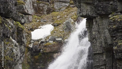 closeup of Jutulhogget Waterfall at the Rondane Nationalpark in the Norwegian mountains in slow motion floating down in a big creek of rough granit stone covered in moss, fern, ice and snow in Norway. photo