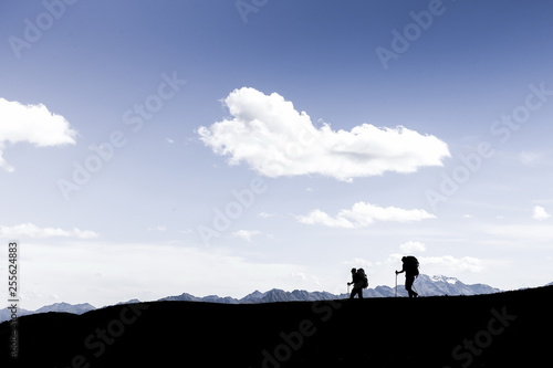 Silhouettes of two hikers walking along the cliff edge