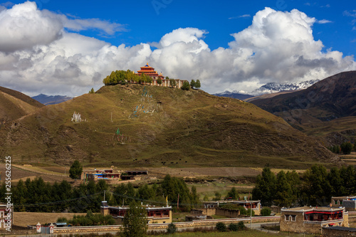 Buddhist Temple on the top of a hill, Tibetan Village of Bamei situated in the grasslands of Sichuan Province, China. blue sky white clouds in the distant background. Tagong and Xinduqiao scenery photo