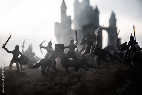 Medieval battle scene with cavalry and infantry. Silhouettes of figures as separate objects  fight between warriors on sunset foggy background.