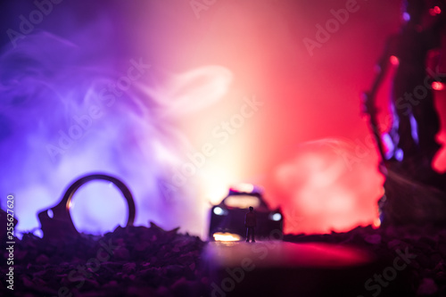 Legal law concept. Silhouette of handcuffs with The Statue of Justice on backside with the flashing red and blue police lights at foggy background. Selective focus