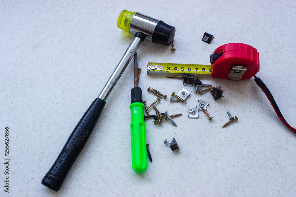screwdriver and tape measure and hammer on white surface screwdriver and tape measure and hammer on white surface