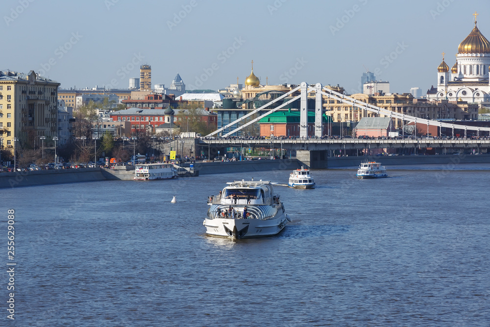 View of the Crimean bridge in Moscow, the river pier on the Crimean embankment and the Cathedral of Christ the Savior in the background, pleasure boats on the Moscow river on a Sunny day