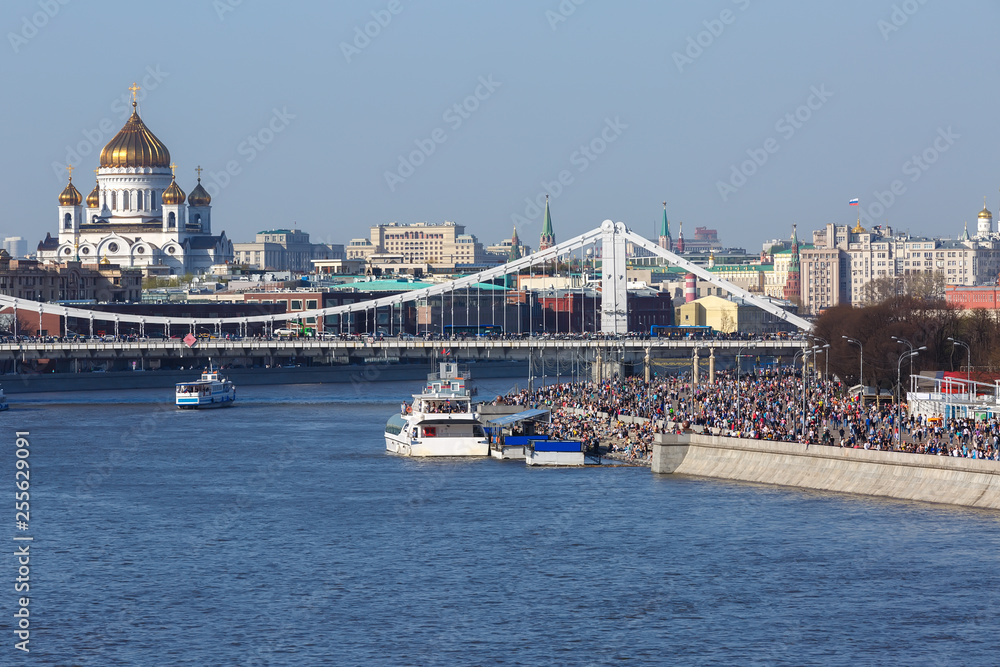 View of the Crimean bridge, Cathedral of Christ the Saviour, Kremlin towers, view from the Moscow river to the Gorky Park embankment with a large crowd of people on a Sunny day