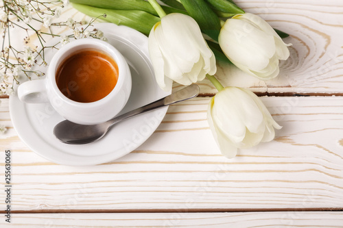 Spring tulips and coffee on a white wooden background, top view. Mother's day background, women's day, morning Birthday