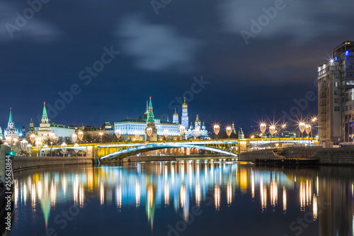 Illuminated Moscow Kremlin and Bolshoy Kamenny Bridge in the rays of setting sun. View from the Patriarshy pedestrian Bridge in Russia. Evening urban landscape in the blue hour