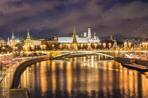 Illuminated Moscow Kremlin and Bolshoy Kamenny Bridge in the rays of setting sun. View from the Patriarshy pedestrian Bridge in Russia. Evening urban landscape in the blue hour