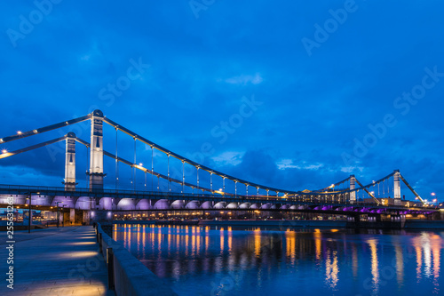 Krymsky Bridge or Crimean Bridge across the Moskva river in Moscow in the rays of setting sun in the evening blue hour with illumination
