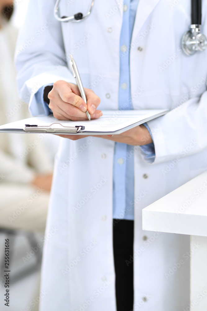 Doctor woman filling up medical form while standing near reception desk at clinic or emergency hospital.Unknown physician at work, hands close-up. Medicine and healthcare concept Doctor woman filling up medical form while standing near reception desk at clinic or emergency hospital.Unknown physician at work, hands close-up. Medicine and healthcare concept