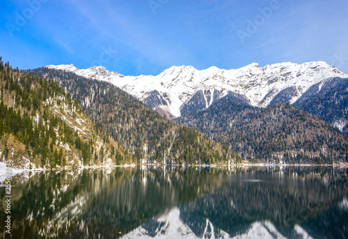 Beautiful mountain lake in the spring. In the background, mountains covered with snow are reflected in the waters of the lake.