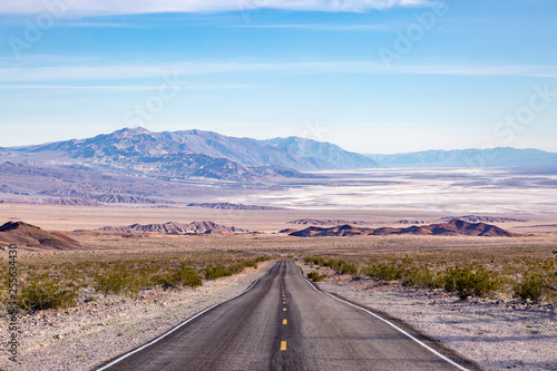 Looking down a long straight road at a vast Death Valley Landscape