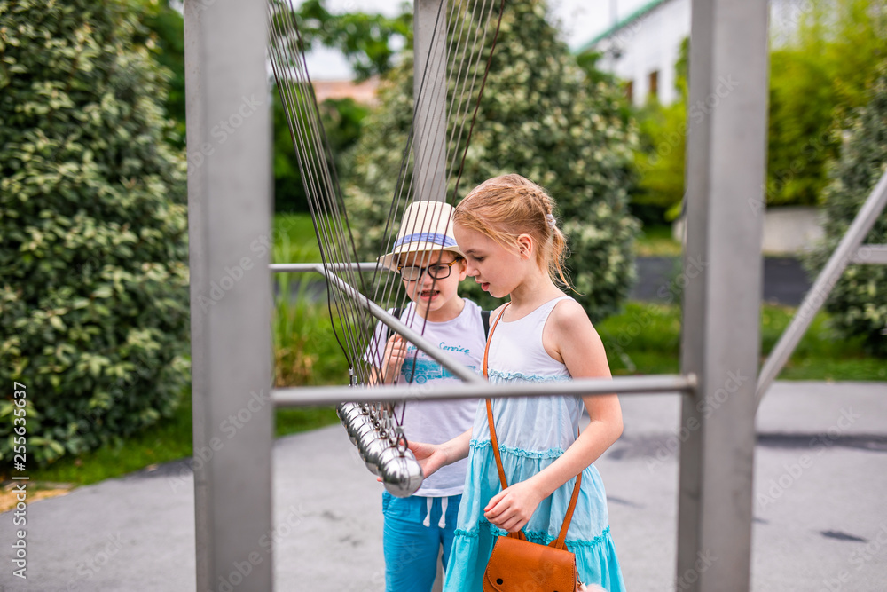 Obraz premium Blonde girl in white and blue dress playing in the playground in the summer park of entertainments