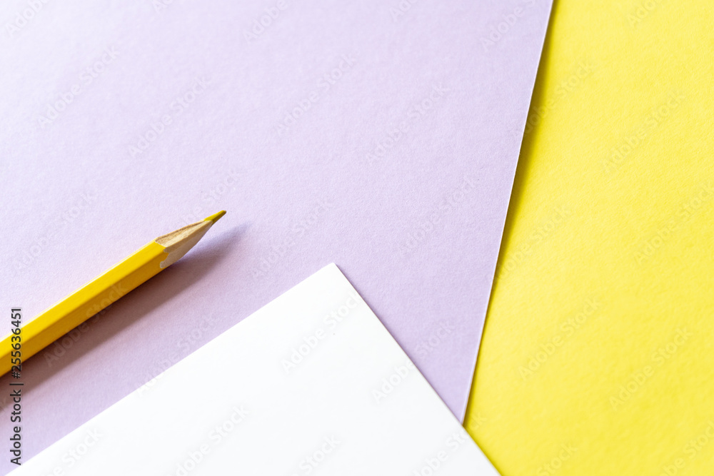 Close-up. Yellow pencil and white piece of paper on yellow and purple background. Art, scool or office shoot Close-up. Yellow pencil and white piece of paper on yellow and purple background. Art, scool or office shoot