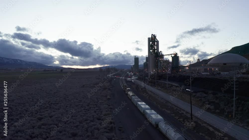 Train Passing By Industrial Power Plant in Evening Twilight, Aerial Drone View Train Passing By Industrial Power Plant in Evening Twilight, Aerial Drone View