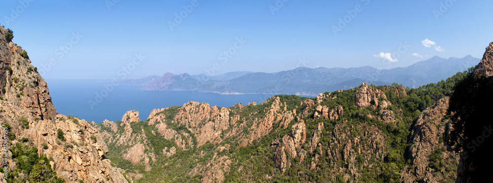 View of sunlit mountains and sea in Calanches area on Corsica island