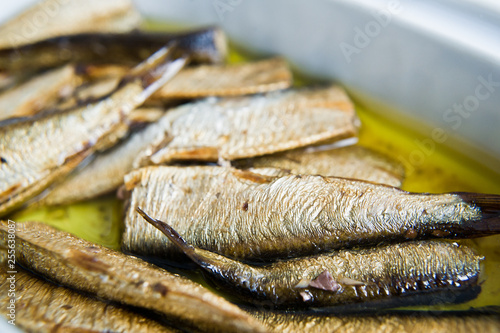 Smoked sprats in oil, ceramic jar. White background, top view, close up.