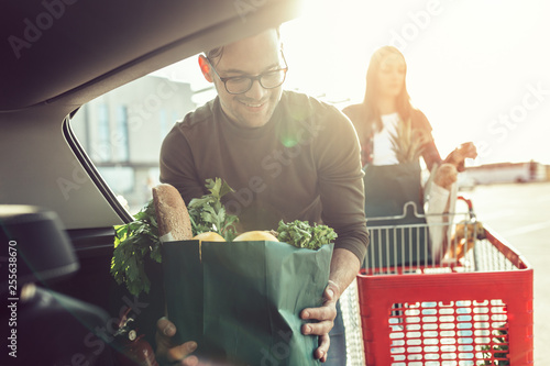 Husband and his pregnant wife after buying food in grocery store or supermarket.