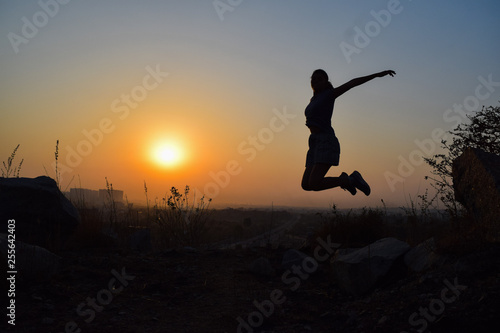 silhouette of young woman jumping in sunrise