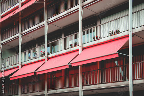 Grey balcony with coral awning in apartment house. Colorful image. Color of the year.